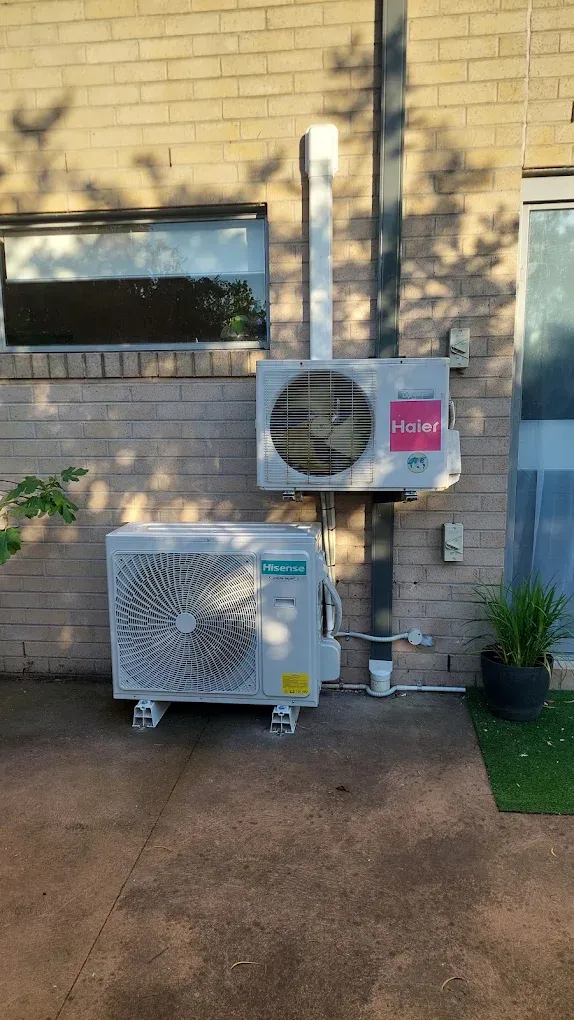 Hisense and Haier outdoor units installed on a brick wall with covers