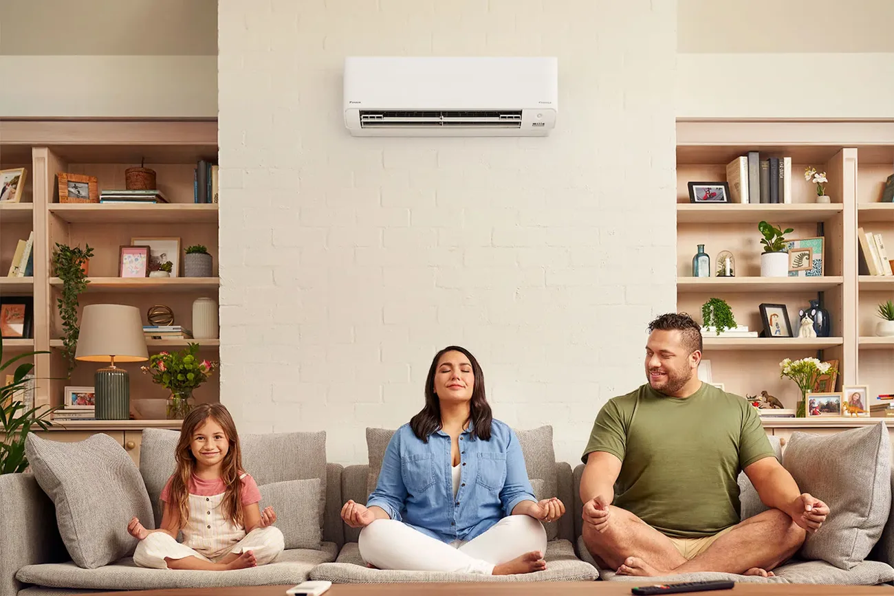 Family relaxing in a comfortable living room beneath a wall-mounted air conditioner